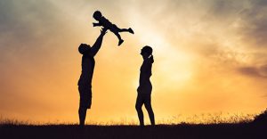 Couple playing with adopted baby in sunset