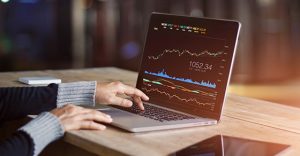 Woman's hands at computer viewing graphs and financial data